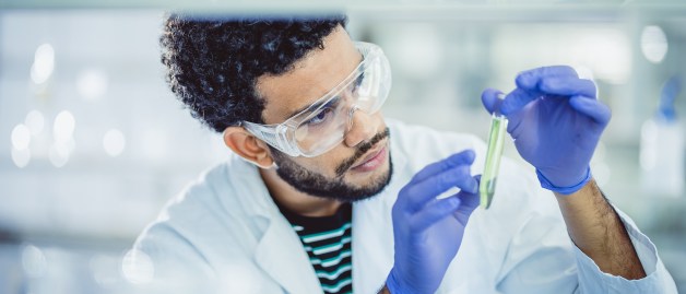 Eine Wissenschaftler in einem modernen Labor untersucht ein Röhrchen mit Flüssigkeit.