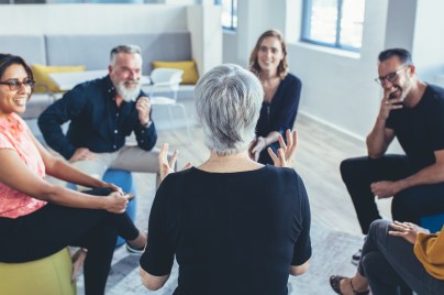 6 Personen sitzen in einem Kreis und unterhalten sich in einer geführten Diskussion