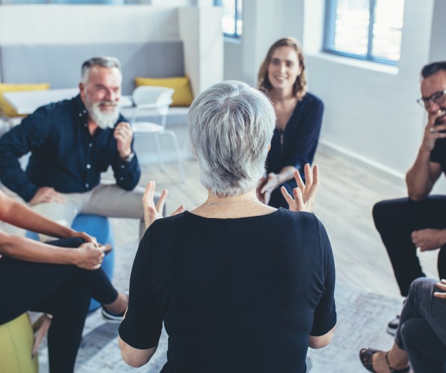 6 Personen sitzen in einem Kreis und unterhalten sich in einer geführten Diskussion