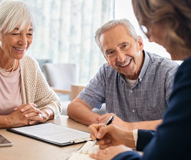 Ein Mann und eine Frau sitzen am Tisch und führen ein Gespräch mit einer dritten Person.