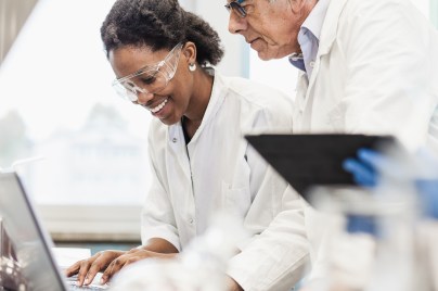 Eine Wissenschaftlerin und ein Wissenschaftler unterhalten sich über Daten auf einem Laptop