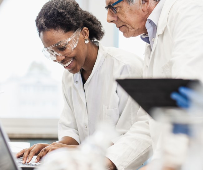 Eine Wissenschaftlerin und ein Wissenschaftler unterhalten sich über Daten auf einem Laptop
