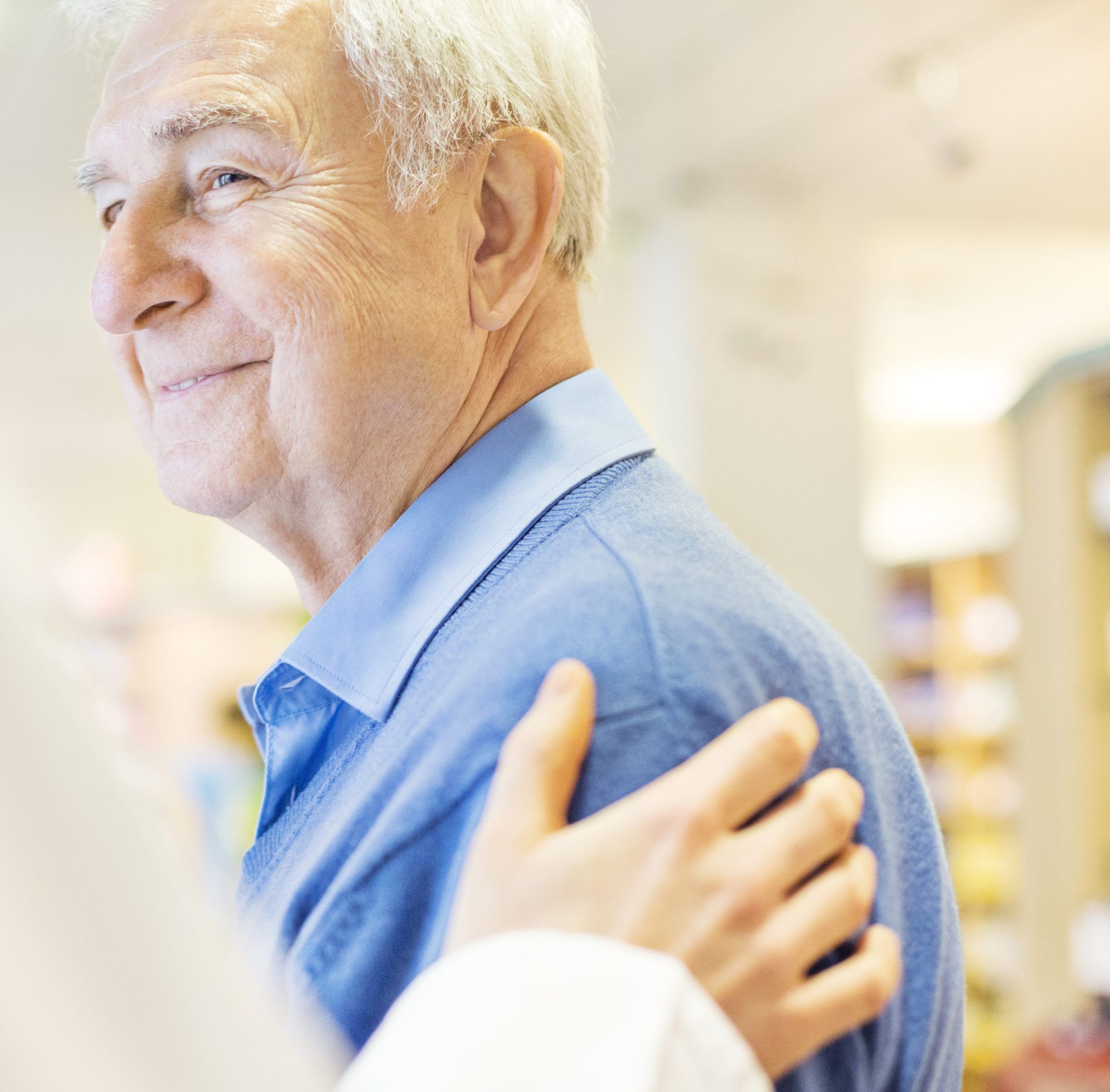 Ein Arzt berührt einen älteren Patienten fürsorglich an der Schulter und spricht ihm Mut zu.