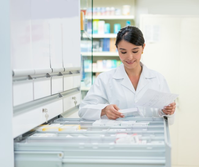 Eine Apothekerin nimmt ein Medikament aus der Medikamentenschublade.