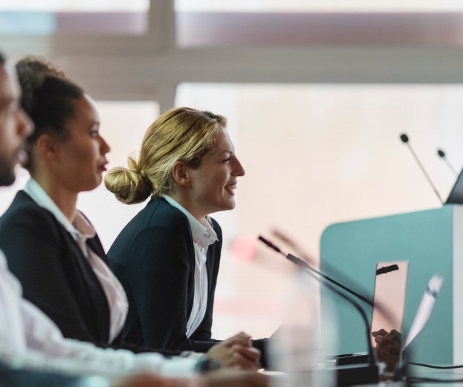 Eine Frau sitzt vor einem Mikrofon und beantwortet Fragen.