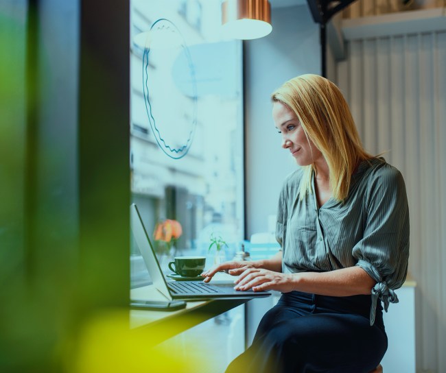 Eine Frau sitzt im Café und arbeitet an ihrem Laptop.