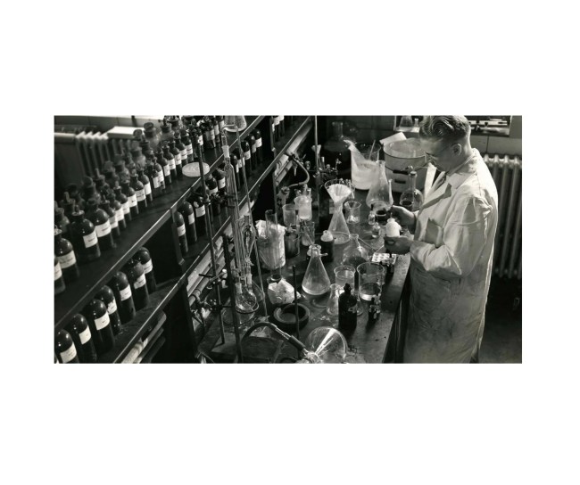 Schwarz-weiß-Aufnahme eines Mannes in einem chemischen Laboratorium der 30er Jahre
