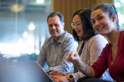 Drei Personen sitzen gemeinsam am Tisch und unterhalten sich