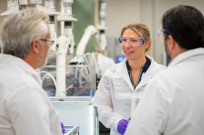 Drei Wissenschaftler:innen unterhalten sich in einem Labor