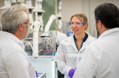 Drei Wissenschaftler:innen unterhalten sich in einem Labor