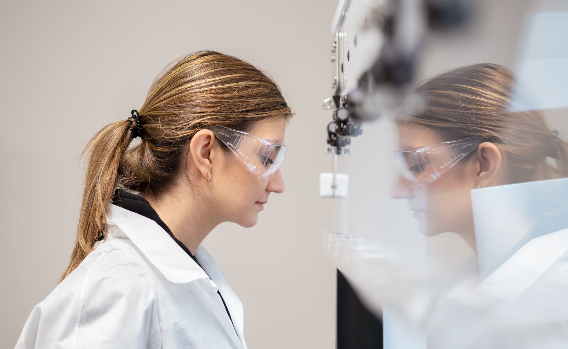 Eine Wissenschaftlerin steht vor einer sterilen Werkbank und sieht hinein.