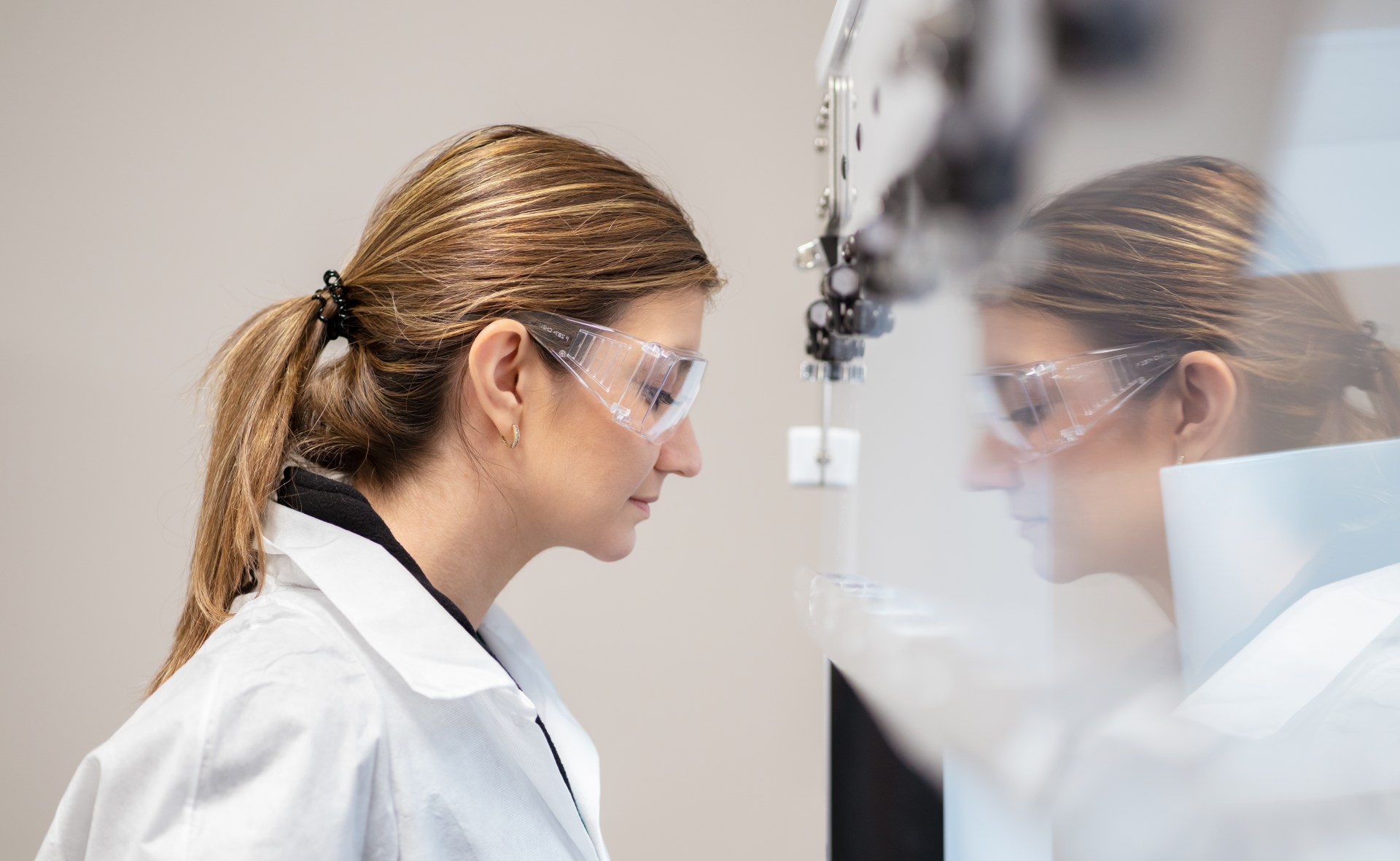 Eine Wissenschaftlerin steht vor einer sterilen Werkbank und sieht hinein.