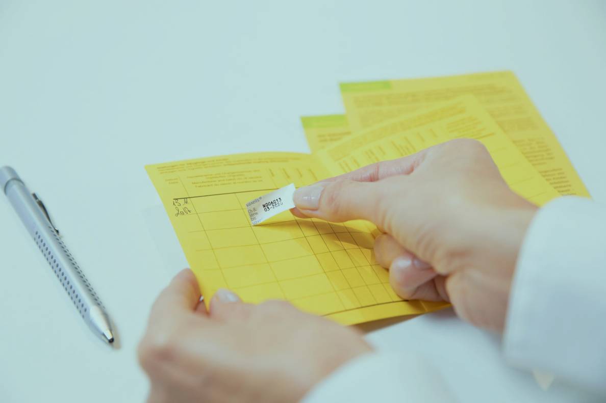 Impfsticker wird in einen Impfpass geklebt