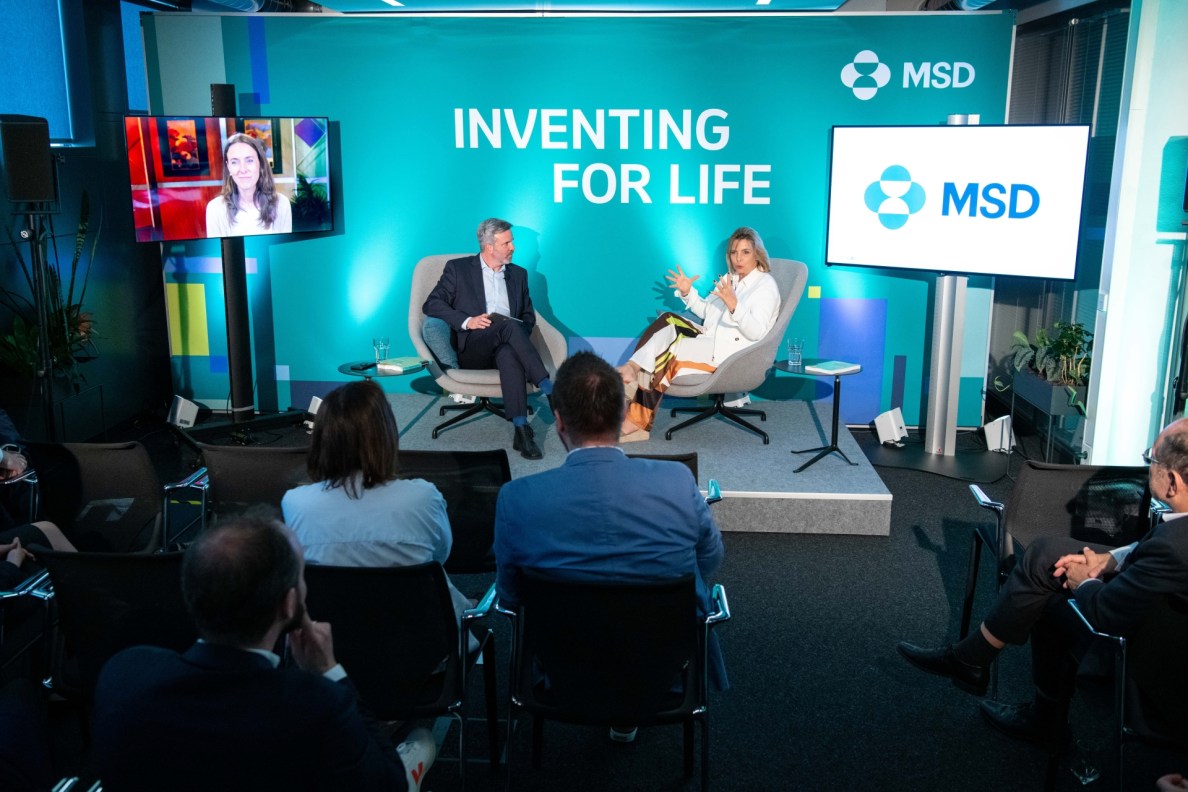 Bild von der Veranstaltung bei MSD. Auf einer Bühne sitzen Angie Gifford (rechts) und der Moderator. Chantal Friebertshäuser ist links vom Moderator digital auf einem Bildschirm zugeschaltet. Das Publikum sitzt mit dem Rücken zum Fotografen.