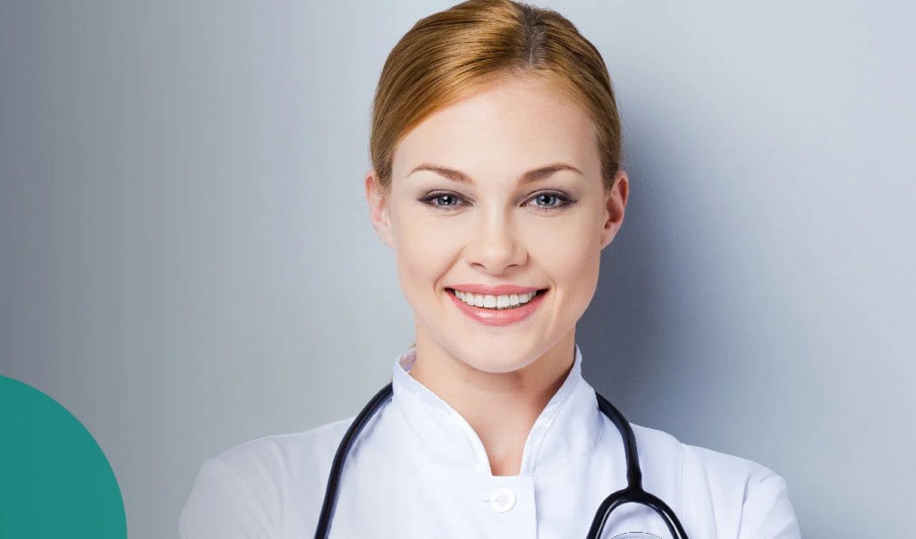lächelnde Frau mit Kittel und Stetoskop vor grauem Hintergrund