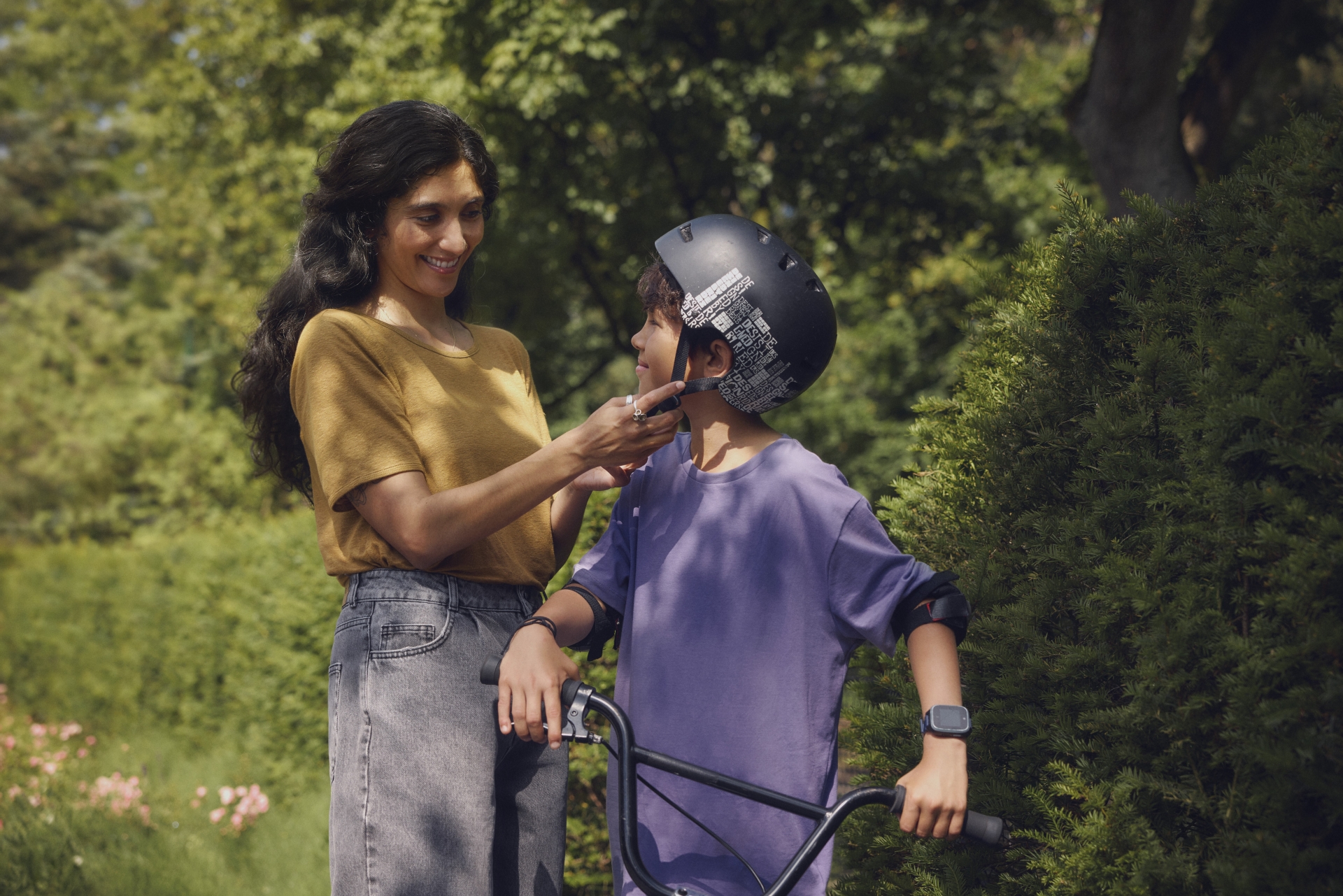 Bild einer Mutter, die ihrem Sohn dabei hilft den Fahrradhelm zu schließen.